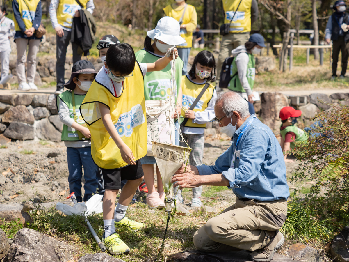 京都市青少年科学センターの藤野 義人さんの指導でビオトープの水を採取する子供達